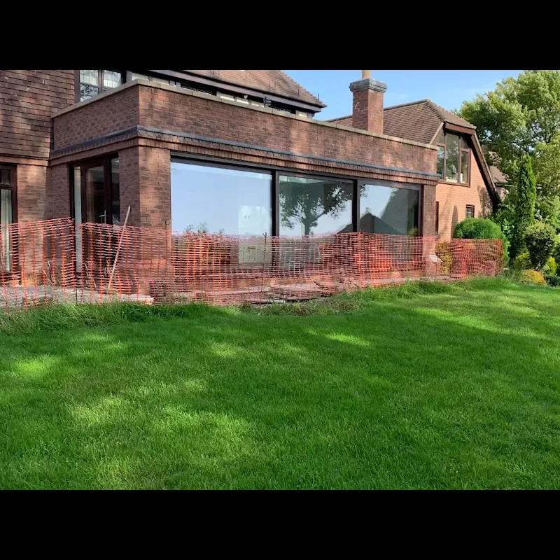 House extension during construction with large glazing panels and orange safety fencing